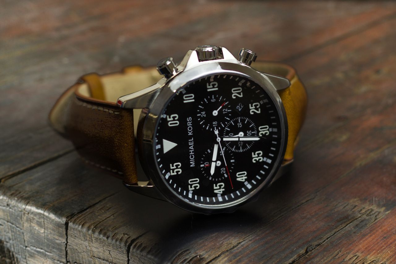 Close-up of a luxury wristwatch on a rustic wooden table, emphasizing design and craftsmanship.