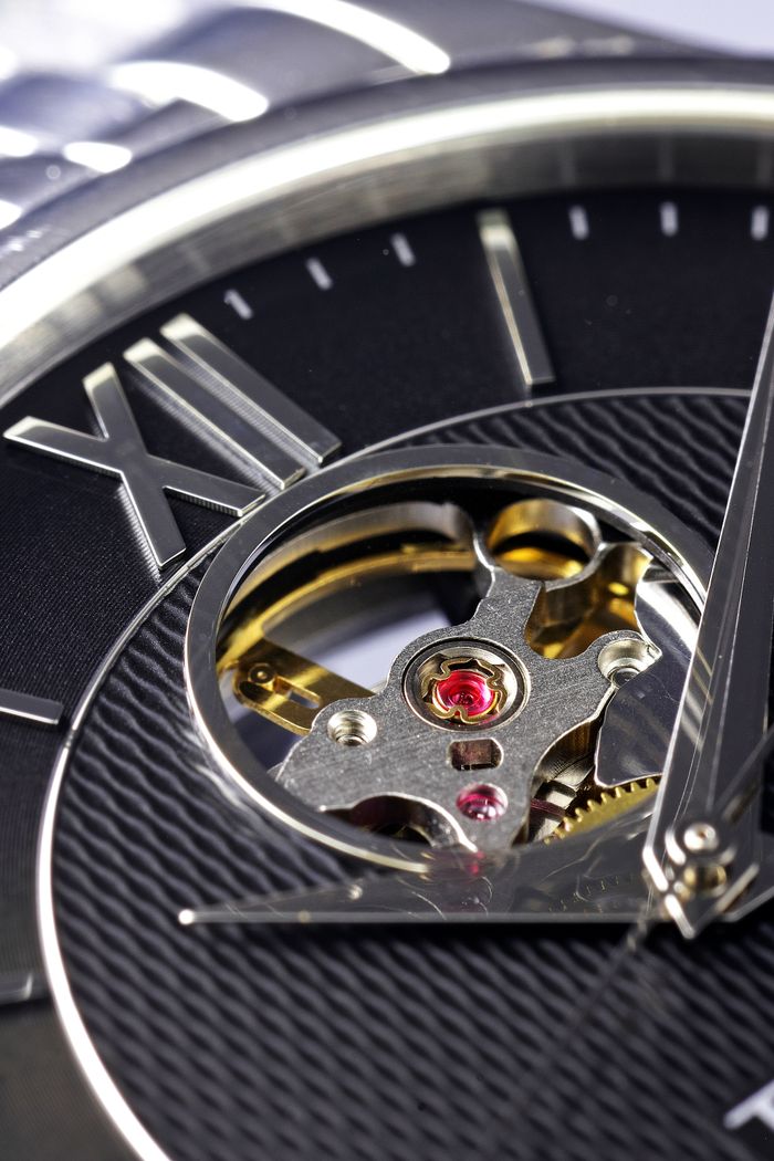 Detailed macro shot of a luxury mechanical watch face featuring Roman numerals and visible gears.