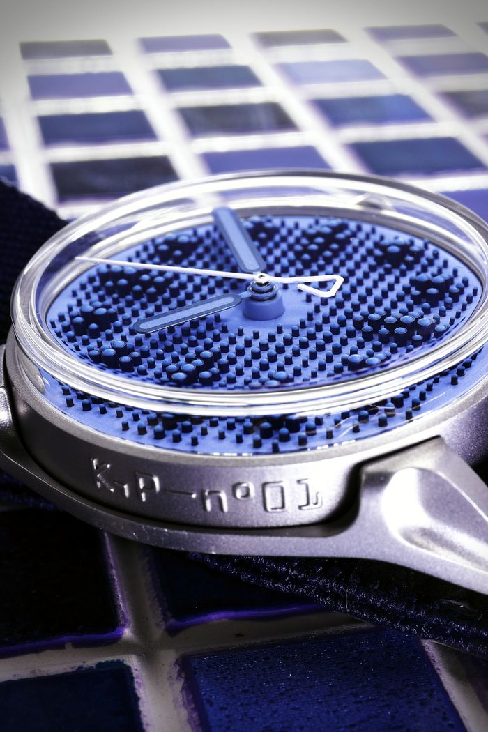 A mechanically intricate watch displayed on textured blue tiles, showcasing unique design.