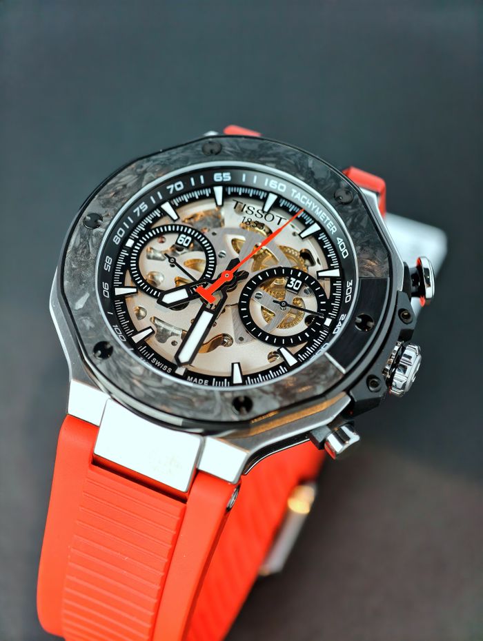 Close-up of a luxury mechanical Swiss watch with a skeleton dial and red strap, showcasing its intricate design.